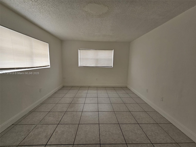 tiled empty room with plenty of natural light and a textured ceiling