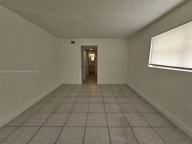 tiled empty room featuring a textured ceiling