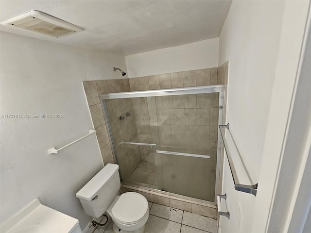bathroom with tile patterned floors, toilet, and a shower with shower door