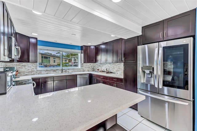 kitchen featuring sink, light tile patterned floors, backsplash, stainless steel appliances, and light stone countertops