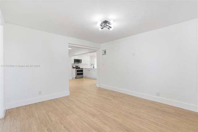 unfurnished room featuring sink and light hardwood / wood-style flooring