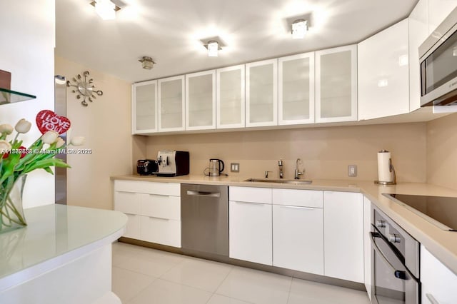 kitchen featuring white cabinetry, sink, light tile patterned floors, and appliances with stainless steel finishes