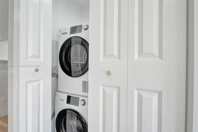 clothes washing area with stacked washer / dryer