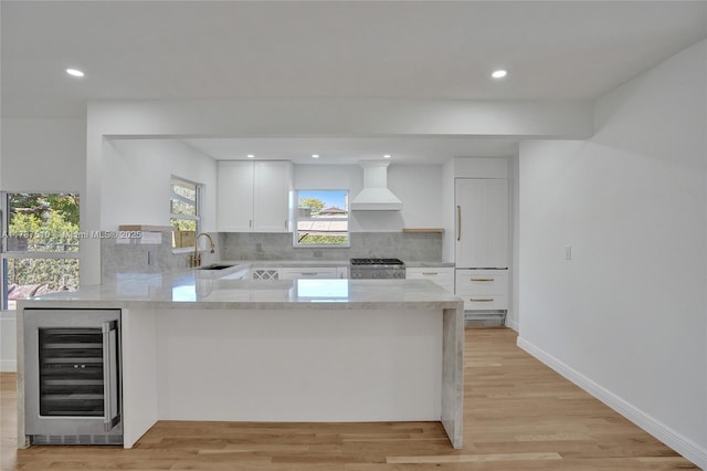 kitchen with sink, white cabinets, beverage cooler, range, and custom range hood