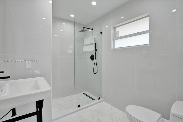 bathroom with toilet, sink, tile walls, and a tile shower