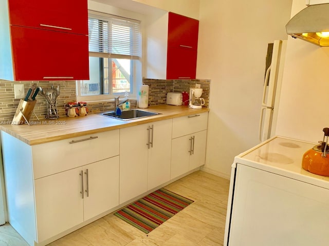 kitchen featuring ventilation hood, sink, white cabinets, decorative backsplash, and range