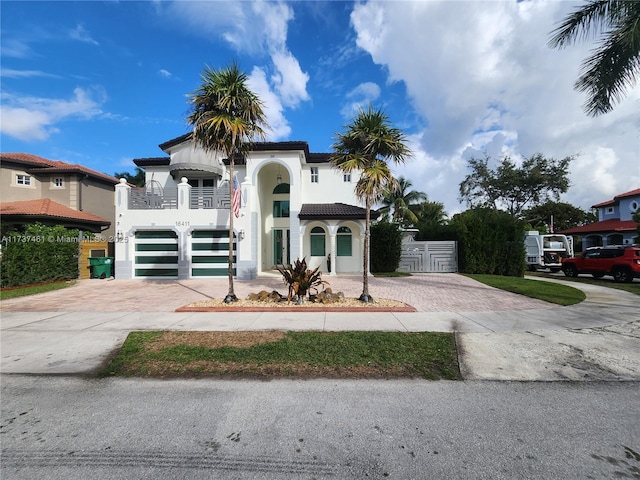 view of front of house featuring a balcony, a tile roof, fence, decorative driveway, and stucco siding