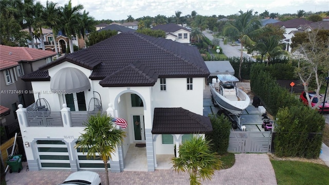 view of front of property featuring a balcony, fence, a tiled roof, french doors, and stucco siding