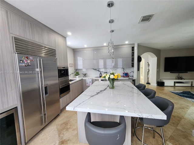 kitchen featuring arched walkways, modern cabinets, built in fridge, and visible vents
