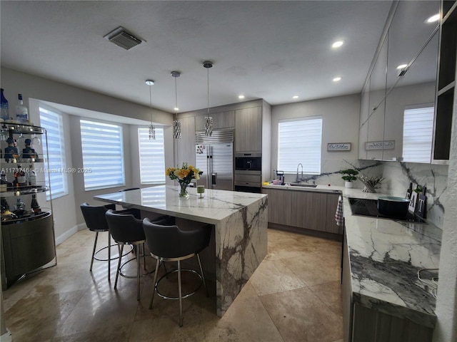 kitchen featuring visible vents, a kitchen island, modern cabinets, appliances with stainless steel finishes, and a breakfast bar area