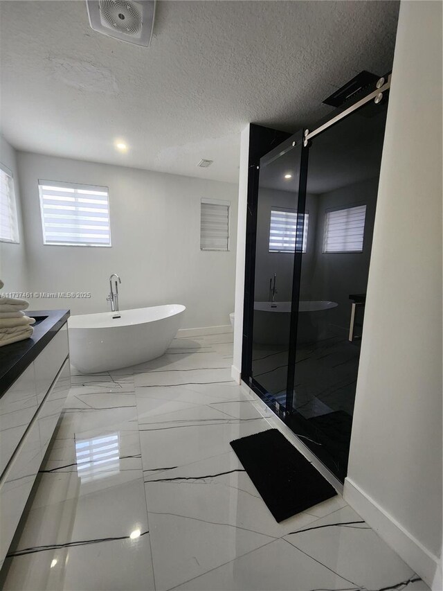 bathroom featuring a stall shower, visible vents, a textured ceiling, vanity, and a freestanding tub