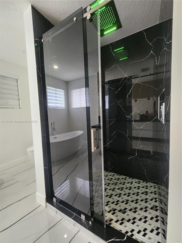 full bath with toilet, a freestanding tub, a marble finish shower, and marble finish floor