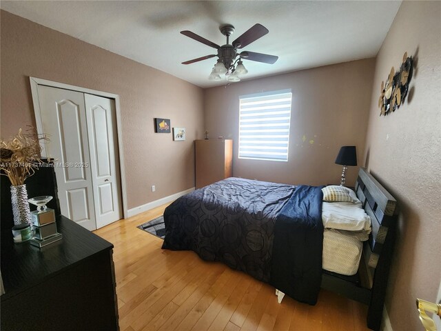 bedroom with a textured wall, a ceiling fan, baseboards, a closet, and light wood-type flooring