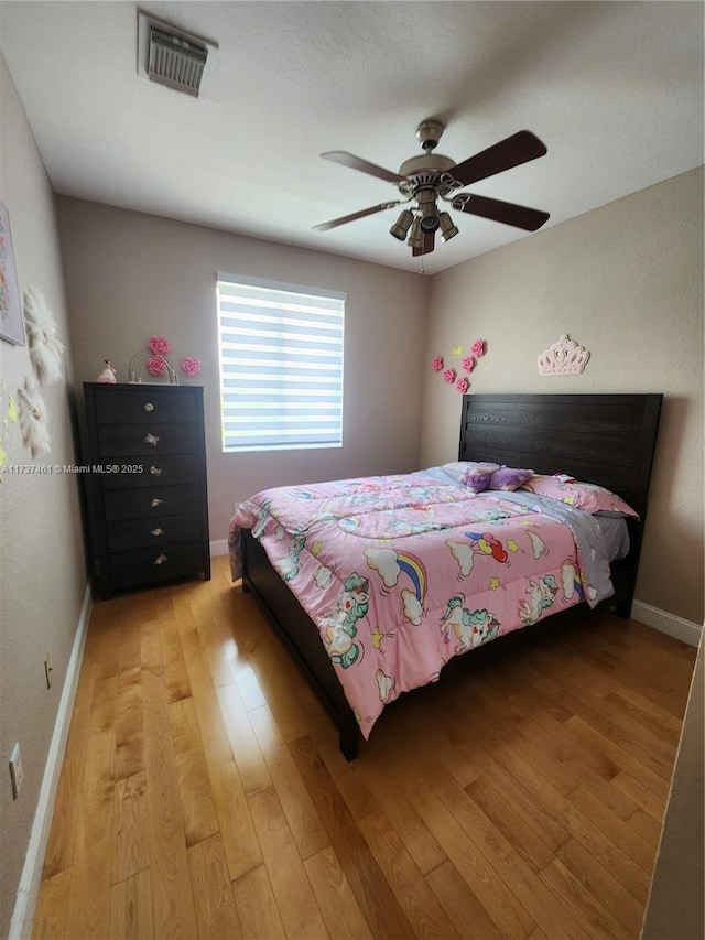 bedroom featuring ceiling fan, light wood finished floors, visible vents, and baseboards