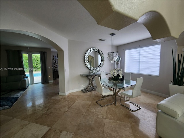 dining space featuring arched walkways, french doors, a textured ceiling, and baseboards