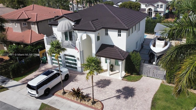 view of front of house with decorative driveway, fence, a tile roof, and stucco siding