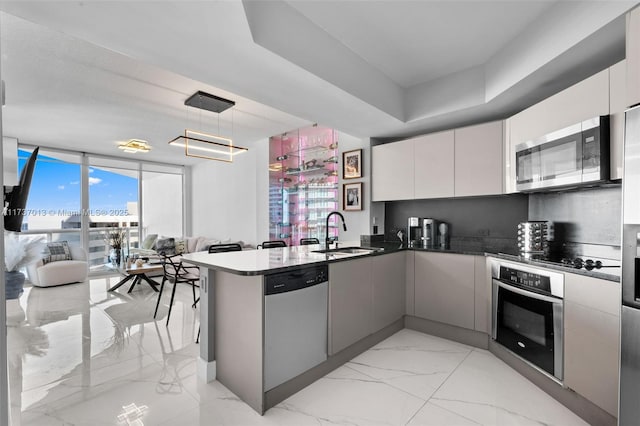 kitchen with appliances with stainless steel finishes, decorative light fixtures, sink, white cabinets, and kitchen peninsula