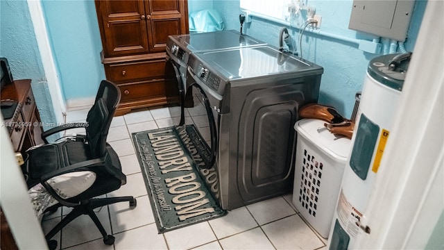 laundry area with electric water heater, washer and dryer, and light tile patterned floors