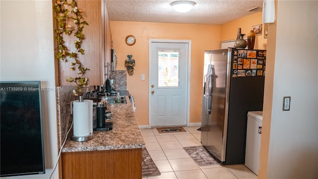 kitchen featuring stainless steel refrigerator with ice dispenser, a textured ceiling, and light tile patterned floors