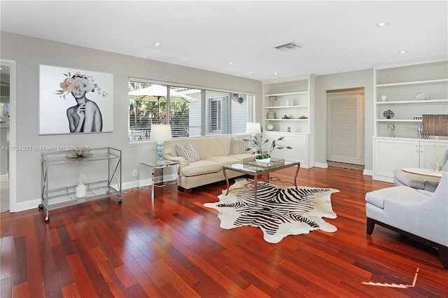 living room featuring dark wood-type flooring and built in features