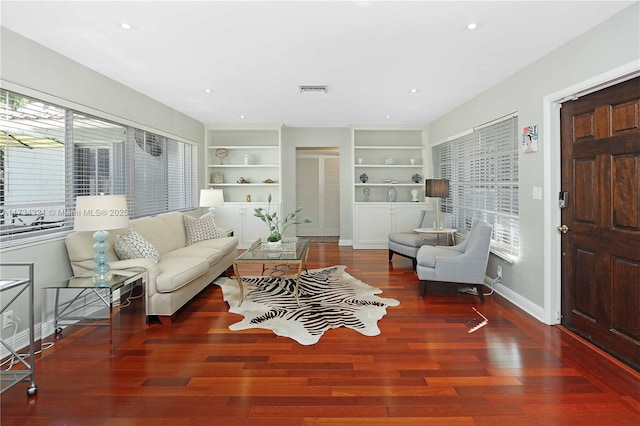 living room featuring plenty of natural light, built in features, and dark hardwood / wood-style floors