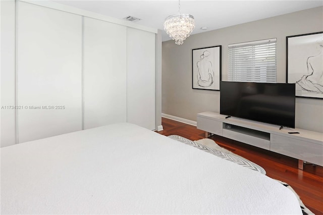 bedroom with a notable chandelier, a closet, and dark hardwood / wood-style floors