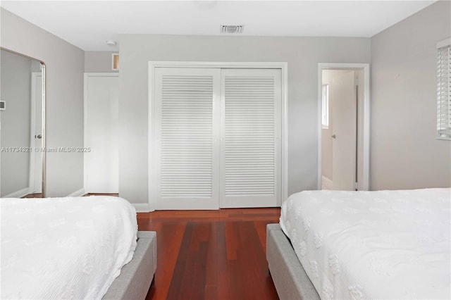 bedroom with dark wood-type flooring and a closet