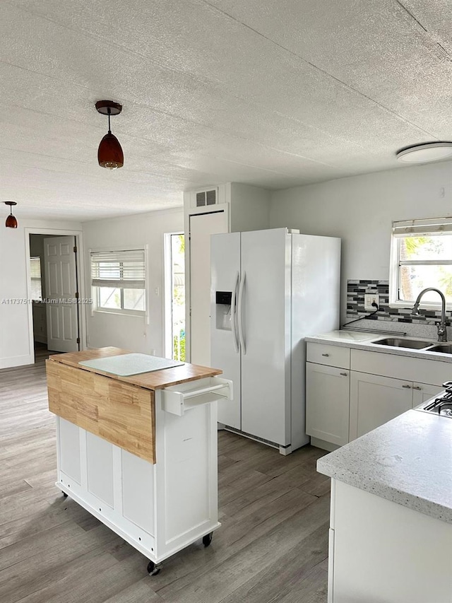 kitchen with a healthy amount of sunlight, visible vents, white fridge with ice dispenser, and a sink