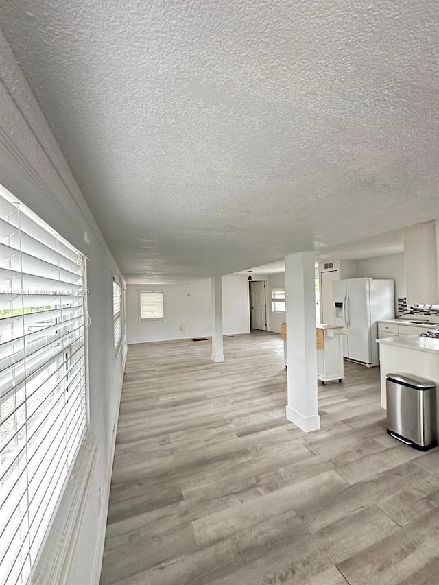 unfurnished living room with a textured ceiling and light wood-style flooring