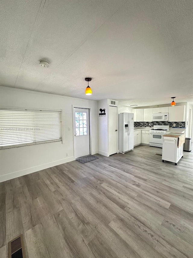 unfurnished living room with visible vents, a textured ceiling, and light wood finished floors