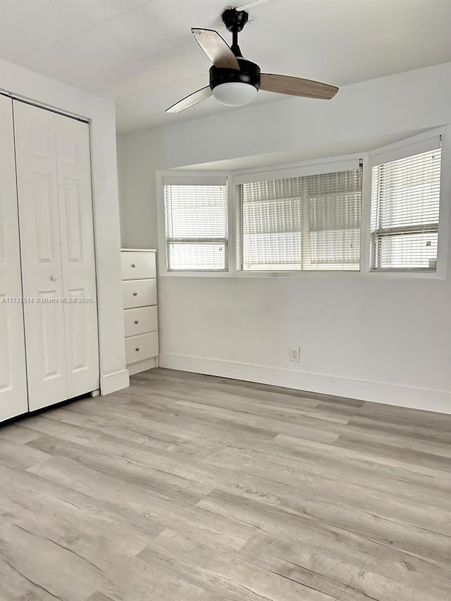 unfurnished bedroom featuring a closet, multiple windows, and light wood-style floors