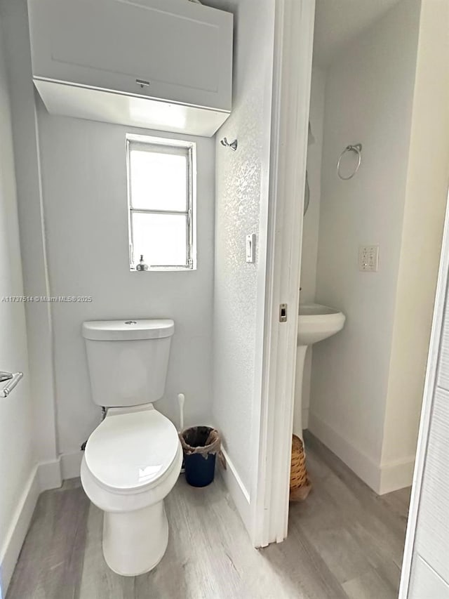 bathroom featuring toilet, wood finished floors, and baseboards