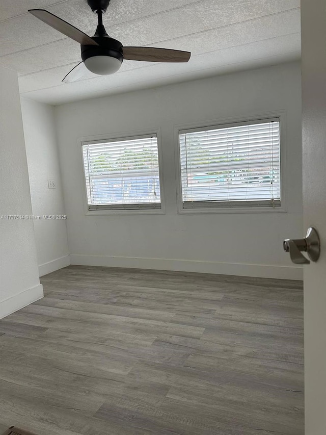 spare room featuring a ceiling fan, baseboards, and wood finished floors