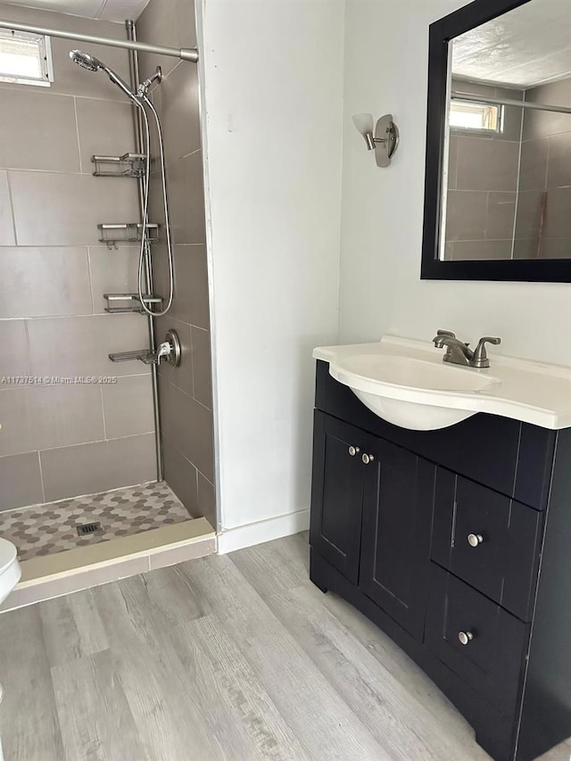 full bathroom featuring vanity, wood finished floors, baseboards, a stall shower, and toilet