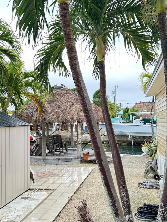 exterior space featuring a water view, a storage shed, an outdoor structure, and a patio area