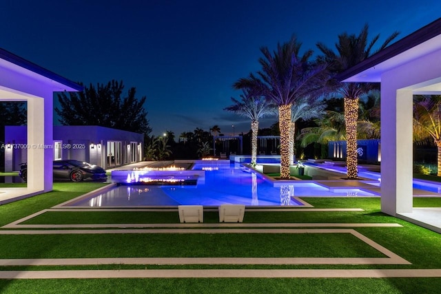 pool at night featuring a yard