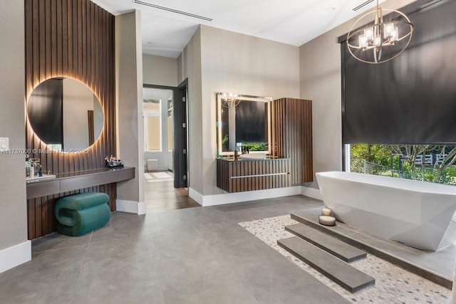 bathroom featuring a bathtub, a towering ceiling, vanity, concrete floors, and a chandelier