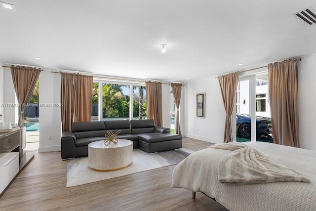 bedroom featuring multiple windows, access to outside, and light hardwood / wood-style floors