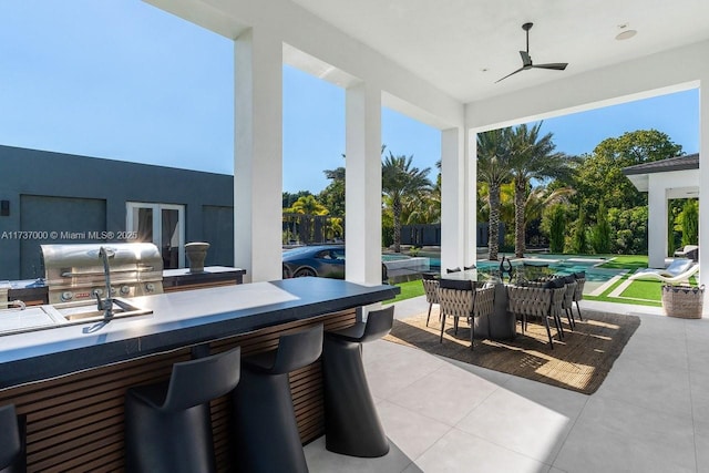 view of patio with a bar, an outdoor kitchen, ceiling fan, and a swimming pool