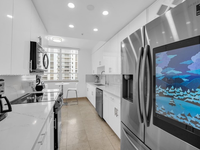 kitchen featuring sink, white cabinetry, light stone counters, stainless steel appliances, and backsplash