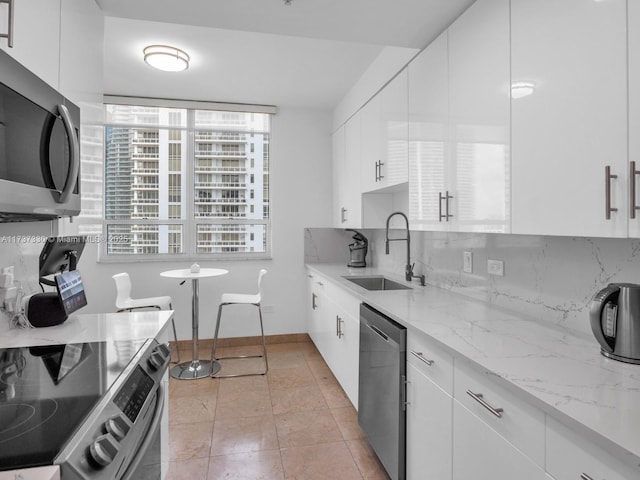 kitchen featuring sink, appliances with stainless steel finishes, light stone counters, white cabinets, and decorative backsplash