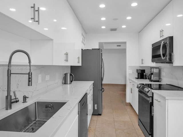 kitchen featuring white cabinetry, sink, stainless steel appliances, and light stone countertops