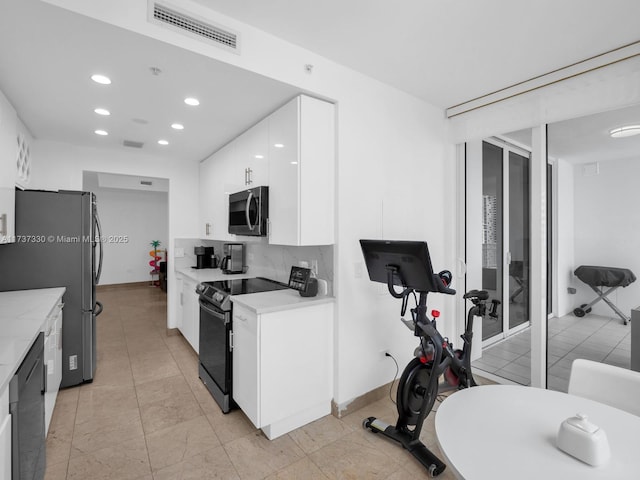 kitchen with appliances with stainless steel finishes, white cabinets, and backsplash