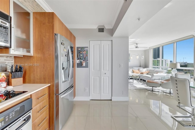 kitchen featuring crown molding, ceiling fan, appliances with stainless steel finishes, tasteful backsplash, and light tile patterned flooring