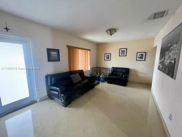 living area with visible vents, a wealth of natural light, and baseboards