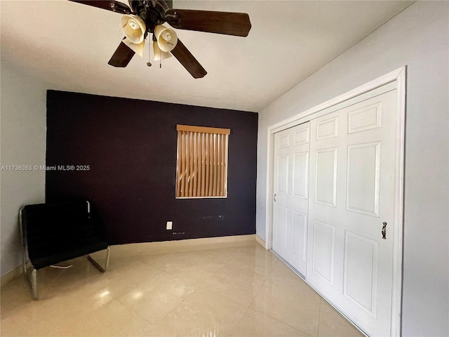 bedroom featuring light tile patterned floors, ceiling fan, a closet, and baseboards