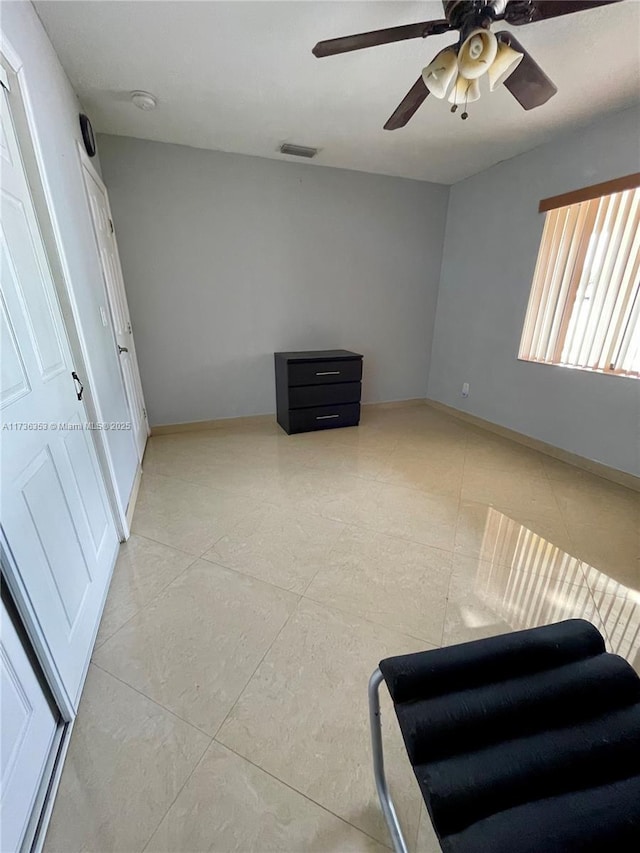 unfurnished bedroom with ceiling fan, light tile patterned flooring, visible vents, and baseboards