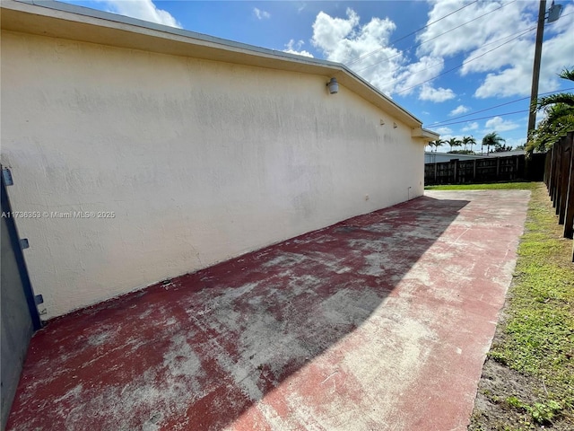 view of property exterior with a patio area, fence, and stucco siding