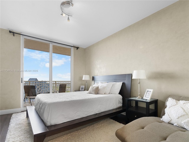 bedroom with a wall of windows, access to exterior, and hardwood / wood-style floors