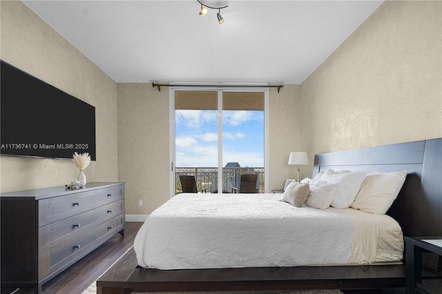 bedroom with dark wood-type flooring, expansive windows, and access to outside